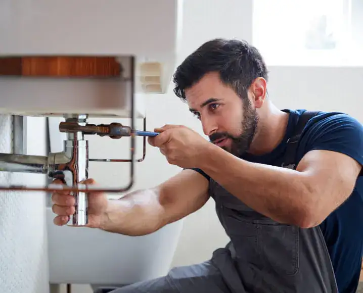 Plumber repairing the pipes under a bathroom sink