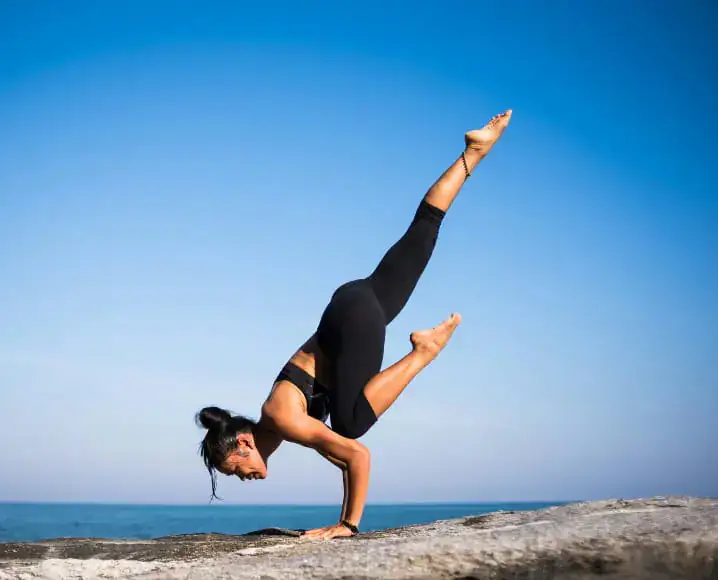 Woman holding a yoga handstand pose by the sea