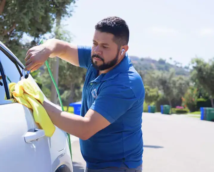 Detailer polishing a white car outdoors