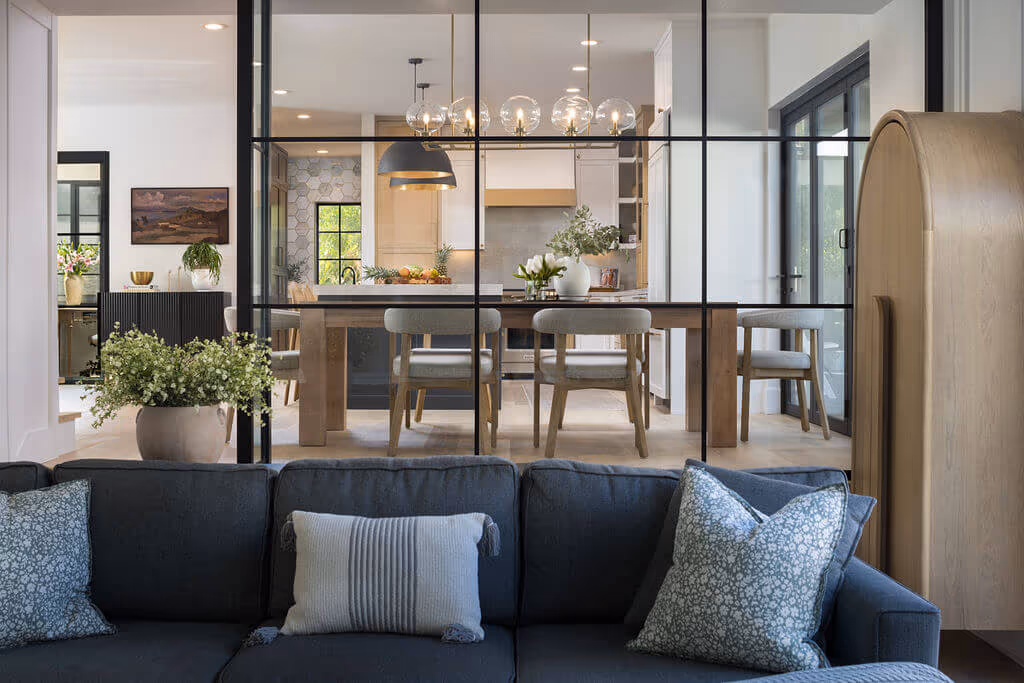 Living room looking through steel-framed glass into a styled kitchen and dining room